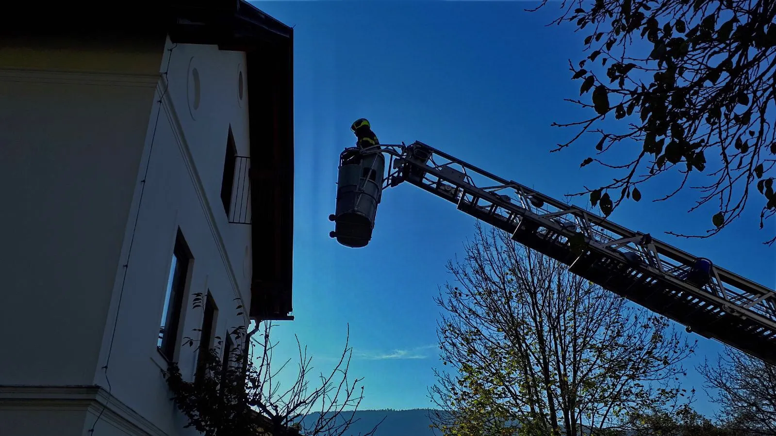 Drehleiter der Feuerwehr im Einsatz vor blauem Himmel