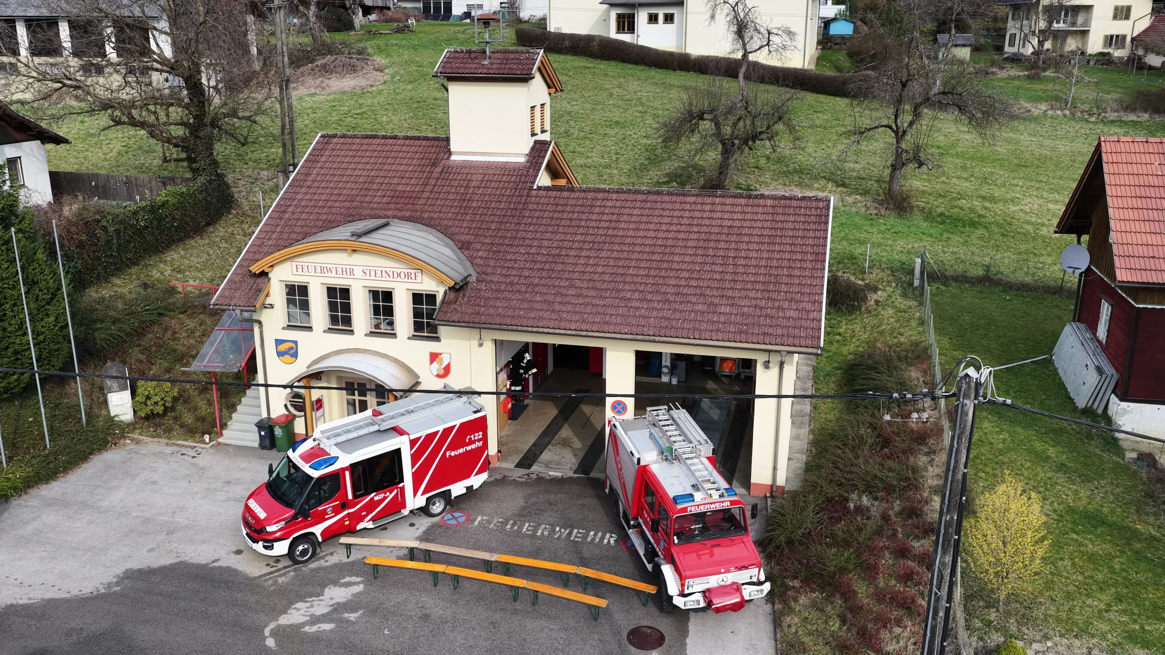 Luftaufnahme des Feuerwehrhauses Steindorf mit beiden Einsatzfahrzeugen vor der Fahrzeughalle